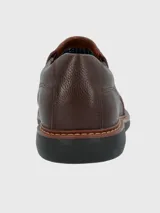 Zapato tipo mocasín Hush Puppies modelo Oregon, confeccionado en cuero vacuno con textura granulada. Presenta un diseño sin cordones con elásticos laterales para un ajuste cómodo, costuras reforzadas y suela de goma EVA de alto rendimiento.