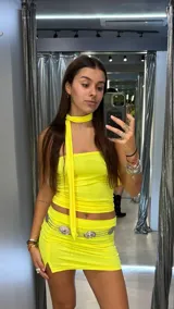 Minifalda de tiro bajo color amarillo neón, confeccionada en tela elástica con un pequeño tajo lateral en el ruedo.