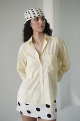 Camisa de rayas verticales rosadas y celestes, con cuello clásico, botonadura frontal y doble bolsillo delantero. Tiene un calce relajado y terminación curva en el ruedo.