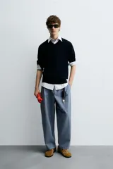 Pantalón de hombre color azul grisáceo, estilo balloon fit, confeccionado en mezcla de algodón y lino. Presenta pliegues en el delantero, cierre frontal con botón y cremallera, bolsillos laterales y bolsillos traseros de plastrón.