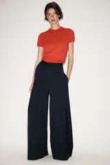 Pantalón de tiro medio con diseño wide leg, confeccionado en tejido con viscosa. Presenta un patrón de rayas diplomáticas, bolsillos laterales ocultos y detalle de pinzas pronunciadas en el delantero. Cierre frontal con cremallera, botón y ganchos metálicos.