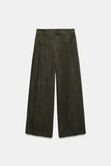 Pantalón verde militar de tiro medio, con bolsillos delanteros, pliegues y tejido con efecto lavado. Cuenta con cierre frontal con cremallera y gancho metálico.