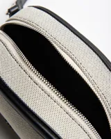 Bandolera chica color beige con detalles y correa ajustable en símil cuero negro, de diseño estructurado con herrajes plateados y logo de la marca en el frente.