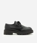 Zapato estilo desert shoe u oxford de Satinato, confeccionado en poliuretano (PU) negro con acabado texturizado. Presenta diseño de punta redonda, cordones al tono y suela gruesa tractorada de goma.