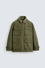 Cazadora de estilo militar en color verde oliva, confeccionada en algodón con efecto lavado. Presenta un diseño de corte relajado con cuello doble, cierre frontal con cremallera oculta por solapa con botones a presión, cuatro bolsillos frontales de plastrón con solapa y puños ajustables con botón.