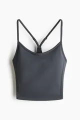 Top deportivo gris oscuro de tejido funcional con tecnología DryMove, escote amplio y breteles finos que se cruzan en la espalda.
