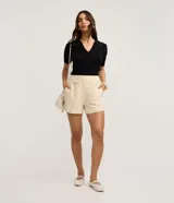 Blusa de punto azul marino con cuello polo, escote en V y mangas cortas. Detalle de mini perlas aplicadas en el cuello.