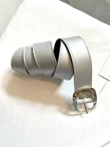 Cinto plateado de cuero forrado con hebilla rectangular metálica plateada.