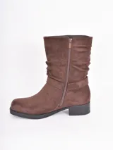 Bota corta de gamuza color marrón con efecto arrugado en la caña, cierre lateral y detalle de tira con hebilla metálica circular en el tobillo.