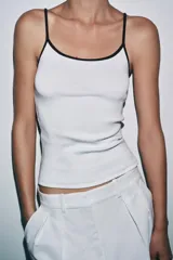 Camiseta de tirantes finos, corte ajustado al cuerpo y escote redondo. El cuerpo es de tejido azul marino jaspeado y el ribete del escote y los tirantes son de color rojo.