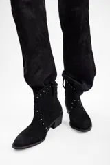 Botas texanas cortas de cuero vacuno color negro, con diseño de punta fina y taco cuadrado. Presentan detalles de tachas metálicas plateadas distribuidas en la parte frontal y lateral.