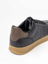 Championes urbanos de diseño minimalista en color blanco, con detalle de talón en color marrón oscuro y suela de goma color caramelo.
