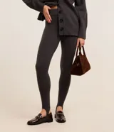 Pantalón legging de punto color gris oscuro, tiro alto, con cintura elástica y cinta estribo para ajuste en el pie.