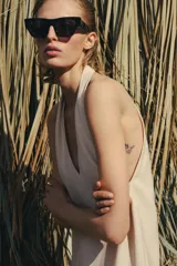 Top halter color crudo, de escote en V y diseño confeccionado en hilatura con mezcla de viscosa. Presenta bajo asimétrico con flecos al tono y cierre en la espalda.