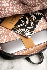 Mochila negra con textura símil cuero de cocodrilo, con dos compartimentos principales con cierre y asa de mano en la parte superior.