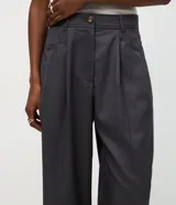 Pantalón de sastrería modelo wide leg color gris oscuro, con pliegues frontales, cintura estructurada con presillas y bolsillos laterales funcionales.