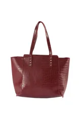 Cartera tipo tote bag de cuero sintético con relieve tipo cocodrilo, color bordó, con doble asa de hombro y detalles de tachas metálicas doradas en la base de las asas.
