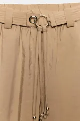 Pantalón recto color beige de tiro medio, con cintura elástica, bolsillos delanteros y cinturón ajustable con hebilla metálica dorada.