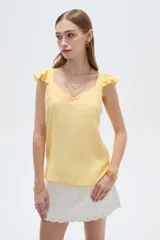 Musculosa amarilla de viscosa, con cuello en V y breteles anchos decorados con volados. Presenta un corte holgado.