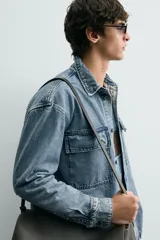 Sobrecamisa de denim de algodón con efecto lavado, corte regular fit, cuello solapa, cierre frontal de botones, manga larga con puños abotonados y dos bolsillos frontales con solapa en el pecho.