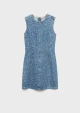 Vestido corto de denim con efecto desgastado, sin mangas y cuello redondo. Presenta un diseño entallado con costuras decorativas verticales y cierre de cremallera en la parte posterior.