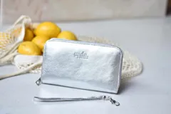 Billetera plateada con cierre y correa de muñeca extraíble.