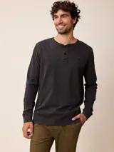 Remera de manga larga con cuello redondo y cierre frontal parcial con botones. Presenta un diseño de color sólido con un pequeño logo bordado en el pecho.