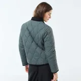 Chaqueta corta con estampado floral en tonos rosa y celeste sobre fondo negro. Tiene cuello mao y cierre frontal con botones a presión.