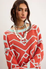 Buzo oversize de punto color marfil con diseño geométrico jacquard en tonos rosado, amarillo, celeste y marrón. Cuenta con cuello redondo y mangas largas.