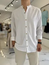 Camisa de lino blanca de manga larga con cuello mao y botones delanteros en tono marrón.