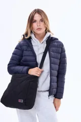 Bolso tipo shopper negro con diseño acolchado en forma de rombos. Cuenta con doble asa fija, correa regulable extraíble, bolsillos laterales y un bolsillo trasero con cierre. Incluye un pequeño aplique decorativo en el frente.