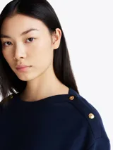 Buzo azul marino de felpa de algodón con cuello barco y botones dorados en los hombros.