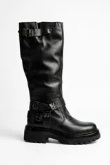 Bota de caña alta confeccionada en cuero negro, con suela track chunky de goma y detalle de tiras con hebillas metálicas en el tobillo y en la parte superior de la caña.
