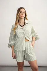 Conjunto de camisa y short a rayas verticales color verde y blanco. La camisa es de corte holgado, con cuello clásico, mangas 3/4 abullonadas y dos bolsillos frontales. El short es de tiro alto con cintura elastizada y cordón ajustable.