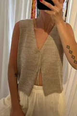 Chaleco de tejido artesanal en color amarillo, con escote en V y cierre frontal mediante lazos anudados. Presenta un diseño sin mangas y corte recto.