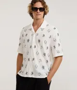 Camisa de manga corta para hombre, corte boxy de inspiración urbana, color blanco con cuello bowling, cierre frontal con botones y detalles de bordado geométrico en relieve.