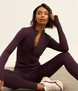 Campera deportiva color borgoña, confeccionada en poliamida y elastano, con cuello alto, cierre frontal con cremallera y bolsillos laterales.