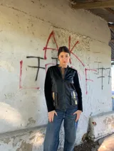 Campera negra de cuero con mangas largas de lana y bolsillos frontales con detalles dorados.