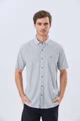 Camisa de manga corta confeccionada en mezcla de lino y algodón, con diseño de rayas verticales en tonos celeste y blanco. Cuenta con cuello camisero, botonadura frontal y bordado sutil en el pecho.