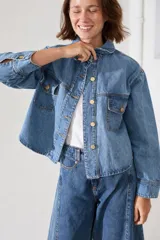 Campera de jean clásica con cierre frontal de botones metálicos, cuello camisero, bolsillos frontales con solapa y mangas largas con puños abotonados.