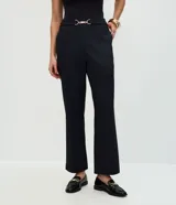 Pantalón de vestir negro de corte recto y ajuste entallado. Presenta una cintura estructurada con un adorno metálico decorativo en el centro y bolsillos laterales. Confeccionado en una mezcla de poliéster, viscosa y elastano.