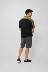 Remera polo negra con corte en hombros y mangas en color verde oliva, con ribete blanco.