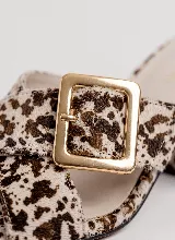Sandalia de taco ancho color dorado, confeccionada en cuero vacuno, con diseño de tiras cruzadas y hebilla metálica decorativa.