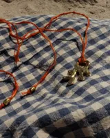 Collar con dije de bronce macizo con forma orgánica irregular, similar a un coral, suspendido de un cordón negro de seda natural anudado.