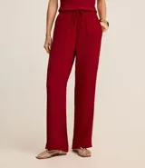 Pantalón pantalona de color rojo, confeccionado en tejido airflow, con elástico y lazo en la cintura.