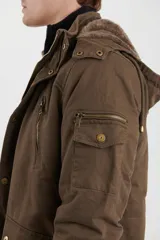 Campera de abrigo estilo parka, color verde militar, con capucha desmontable, cierre frontal con botones y múltiples bolsillos funcionales en pecho, cintura y manga.