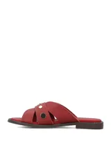 Sandalias planas de cuero rojo con tiras cruzadas y tachas metálicas doradas.