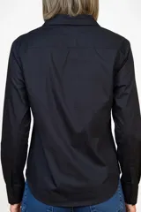 Camisa de corte clásico y diseño cropped, color negro, con cuello camisero, cierre frontal de botones y mangas largas con puños abotonados.