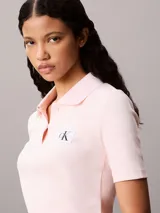 Chomba de Calvin Klein Jeans confeccionada en tejido de algodón con textura acanalada. Presenta cuello tipo polo con cartera de dos botones, mangas cortas y una insignia distintiva de la marca aplicada en el pecho.