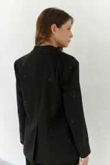 Blazer negro con bordado floral, hombreras, bolsillo interno y botones frontales y en mangas.